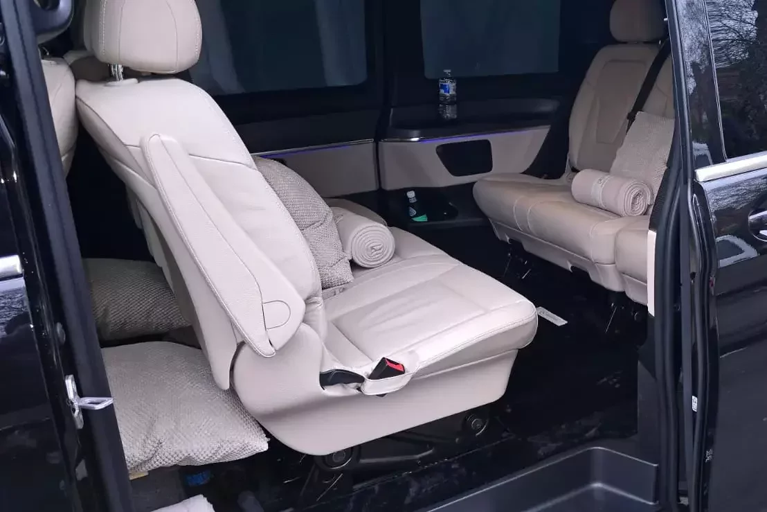 Luxury chauffeur vehicle interior featuring individual reclining leather seats, soft furnishings, and a quiet, private passenger cabin.